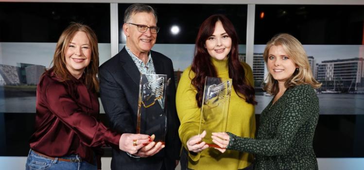 four people holding two awards